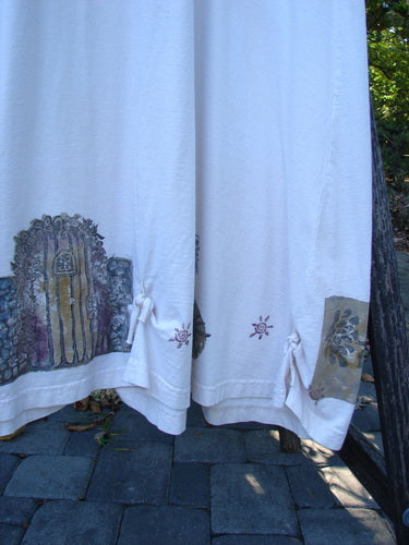 1994 Loop Dress Magic Garden Tea Dye Smaller OSFA displayed with off-white fabric panels. Panels feature rustic door and floral motifs, enhancing the dress's vintage charm, unique to Bluefishfinder.com’s creative expression ethos.