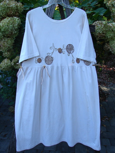 1994 Flower Garden Dress Garden Trail Altered Ecru Size 2, featuring a scooped neckline, three-quarter sleeves, gathered waist with draw-strings, and a botanical motif across the bodice, hanging outdoors.