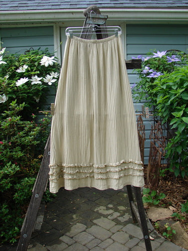 Barclay Rib Silk Triple Ruffle A Line Skirt in Sand, Size 0, on a rack outdoors, embodying Blue Fish Finder's vintage charm and creative freedom for women. Features elastic waist, triple ruffle flutter, and silken texture.