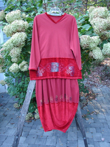 1996 Velvet Arrowhead Sofia Duo Pomegranate Size 1 2 displayed on a hanger. The tunic features a V-neck with decorative hips, paired with a matching skirt, set against lush greenery.