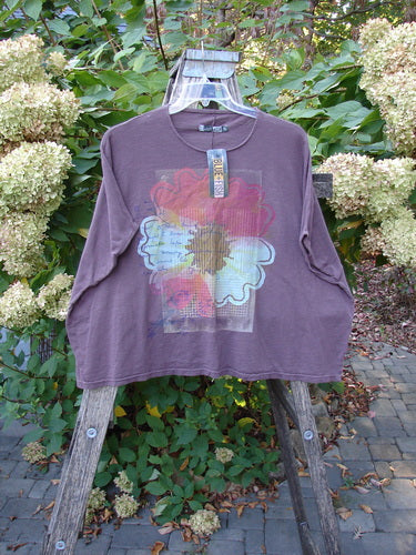 Barclay NWT Cotton Slub Cricket Cap Sleeve Tee Travel By Sun Fig OSFA, featuring a large stylized floral graphic, hangs on a clear hanger over a wooden ladder, with a Blue Fish tag attached.