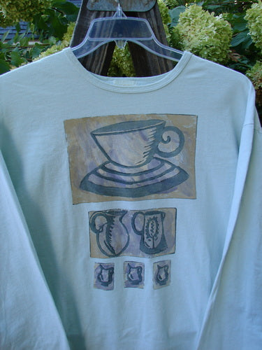 A white long-sleeved tee featuring a tea cup theme paint design, drop shoulders, and a Blue Fish patch. Size 2, mint condition.
