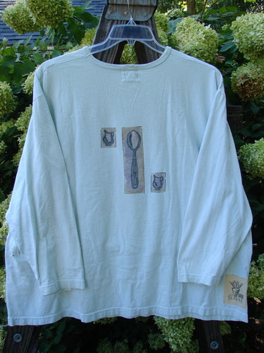 Image: A long sleeved white shirt with a spoon and teapot on it.

Alt Text: 1999 Long Sleeved Tee with Tea Cup Design, Mint Condition, Size 2.