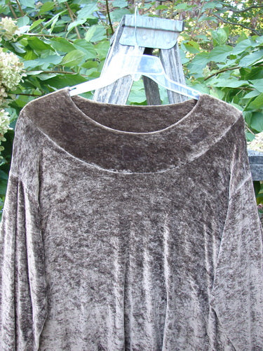 1997 Velvet Surya Top Subtle Celtic Border Mandorla OSFA, hanging on a clear plastic hanger over a ladder, showcasing its swingy hemline and rounded neckline, surrounded by leafy plants and white blossoms.