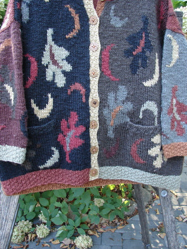 Tara Handknits Star Button Pocket Cardigan Leaf & Moon Brights OSFA, featuring abstract motifs, wooden buttons, and front pockets, draped over a wooden ladder outdoors reflecting BlueFishFinder's unique vintage style.