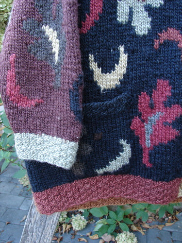 Tara Handknits Star Button Pocket Cardigan Leaf & Moon Brights OSFA draped on a bench, showcasing chunky stitches, metal star buttons, and vibrant motifs, embodying artisanal luxury and individuality.