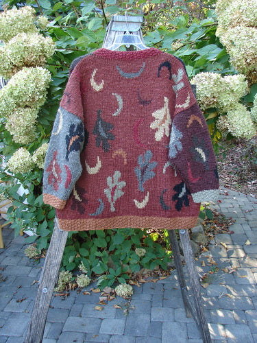 Tara Handknits Star Button Pocket Cardigan Leaf & Moon Brights OSFA displayed on a wooden ladder; features chunky knit with abstract motifs, ribbed edges, and metal star buttons, reflecting BlueFishFinder's vintage style.