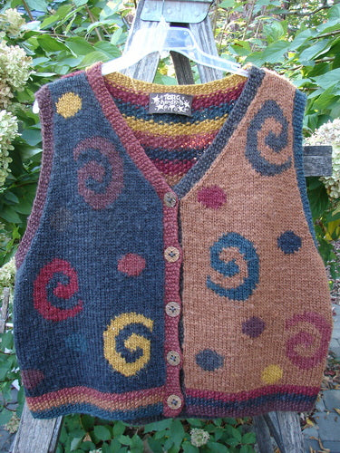 Tara Handknits Back Tab Vest Swirl Polka & Stripe Brights OSFA displayed on a hanger over a ladder, showcasing its intricate, contrasting knit patterns and vibrant swirl motifs against a garden backdrop.