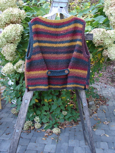 Tara Handknits Back Tab Vest Swirl Polka & Stripe Brights OSFA showcased on a wooden stepladder, featuring hand-knit detailing with ribbed neckline and metal star buttons, reflecting vintage Blue Fish Clothing's creative individuality.