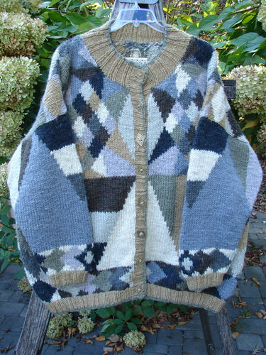 Tara Handknits Diamond Button Oversized Cardigan Geometric Naturals OSFA, featuring a luxurious, geometric pattern with ribbed edges and diamond-shaped metal buttons, displayed outdoors against a leafy garden backdrop.