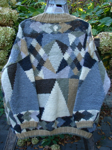 Tara Handknits Diamond Button Oversized Cardigan Geometric Naturals OSFA draped on a wooden ladder, showcasing its intricate patchwork of geometric patterns and ribbed accents, emphasizing its handcrafted, vintage charm.