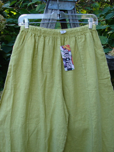 Barclay NWT Linen Alchemist Pant Unpainted Citron Size 0, featuring loose-fitting lime-green linen with elastic waistband, side pockets, sectional panels, and a lower leg bell accent, hanging outdoors on a clear hanger.