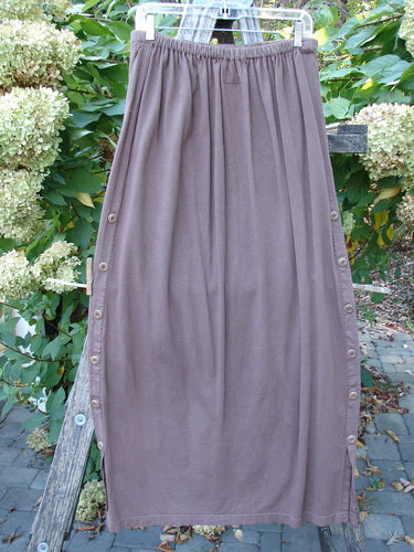 Barclay Button Panel Skirt Vegetable Sepia Size 2 hanging outdoors, showcasing a long brown knit design with an elastic waistband and side buttons, highlighting the casual maxi style perfect for fall.