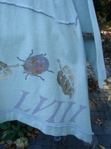 1998 Botanicals Orchard Jacket Plante Grasshopper Altered Size 1, featuring a stylized ladybug motif and Roman numerals LVIII, hangs on a stand, showcasing its wide-banded A-line hem and drop shoulders.
