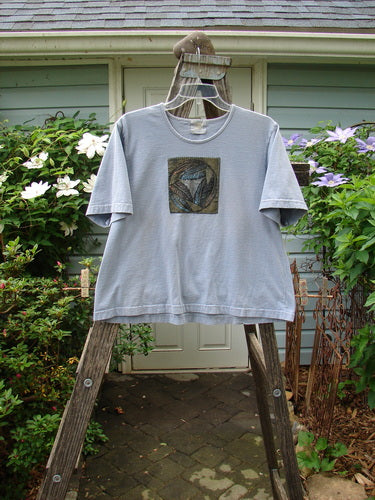 1999 Patched Short Sleeved Crop Tee Feather Bluestone Size 2 displayed on a rack, featuring a distinctive feather theme paint and a signature Blue Fish patch, highlighting its vintage charm.