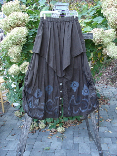 Barclay Batiste Split Button Pant Skirt Celtic Mocha Size 0, featuring an asymmetrical, tiered design with a pointed draped overlay, button details, and a decorative hem pattern, displayed on a wooden ladder.