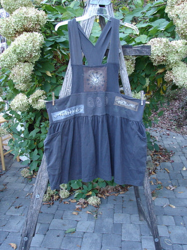 1995 Overall Jumper Fish Space Briquette OSFA displayed outdoors on a wooden ladder, showcasing its pinafore style with a gathered skirt, oversized pockets, and crisscross straps, reflecting Bluefishfinder.com's vintage, creative ethos.