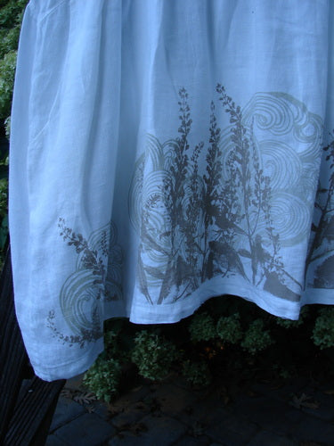 A close-up of a Barclay Linen Studio Pullover Dress Breeze Fern White Size 2. Flouncy lower skirt, drop and gathered waistline, wide hem sweep, and unique figure 8 front bodice seams.