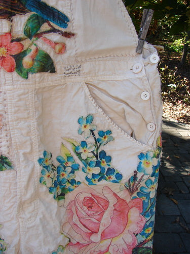 Magnolia Pearl Applique Benjamin Overall Birdie Bouquet Moon OSFA hangs on a clothesline, showcasing hand-painted floral fabric, button details, and a pocketed bib, embodying Bluefishfinder's vintage, expressive style.
