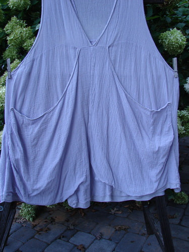 Image alt text: Barclay Gauze Farmer Jen Sleeveless Tunic, Lilac, Size 2, on clothes rack, with stacked lower pocket ensemble, widening A-line shape, deep V-shaped neckline, and deep arm openings.