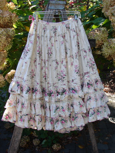 Magnolia Pearl Penelope Skirt Des Rosiers Floral Idealist OSFA: Cream tiered skirt with pink-green floral print, drawstring waist, pintuck accents, four lacy ruffle layers, hand-stitched patches, hanging outdoors.