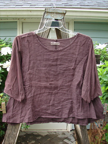 Barclay Cotton Sleeved Linen Crop Top Unpainted Fig Size 1 displayed on an outdoor hanger, showcasing its rounded neckline, three-quarter sleeves with curly edges, and A-line shape.