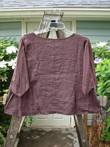 Barclay Cotton Sleeved Linen Crop Top Unpainted Fig Size 1 displayed on a wooden hanger, featuring a rounded neckline, three-quarter sleeves with curly edges, and an A-line shape.