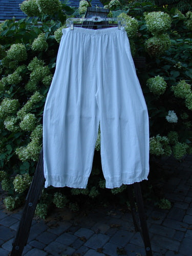 Barclay Batiste Carousel Flutter Pant Stripe White Size 2: A pair of white pants on a rack, featuring a slightly cropped length, super stripe ruffle lowers, and a wide flowy shape. Perfect for spring or summer with a full elastic waistline and generous hip measurements.