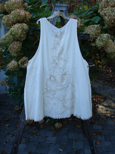 Barclay Slub Figure 8 Lace Pocket Pinafore Dress Soft Floral Crème Size 2 hung on a wooden ladder, showcasing its unique figure-eight seams, leaf-imprint design, and lacy hem accents.