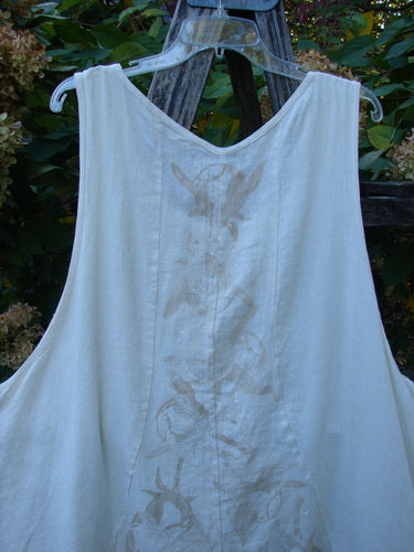 Barclay Slub Figure 8 Lace Pocket Pinafore Dress in a soft floral crème, featuring drop side pockets, figure-eight seams, and lacy hem accents, displayed on a wooden trellis.