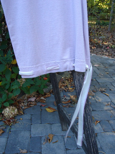 1999 Ribbon Pant Unpainted Orchid Size 1, draped over a rustic frame, showcases silk ribbon ties at the hem, reflecting Bluefishfinder.com's vintage charm with its playful, versatile design in organic cotton.