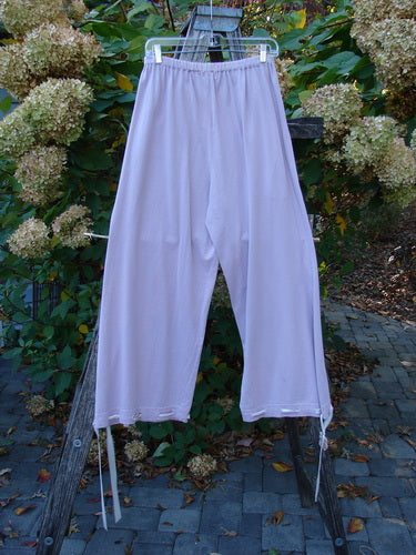 1999 Ribbon Pant Unpainted Orchid Size 1, featuring loose-fit drawstring style with elastic waist, deep front bubble cargo pockets, and buttoned cuffs, hanging from a ladder, embodying playful, vintage Blue Fish charm.