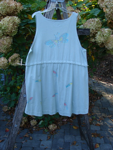 Barclay Little Tree Vest Dragonfly Fish Cucumber Size 1: A toddler's sleeveless sundress with butterfly embroidery and colorful leaf prints, displayed on a ladder outdoors amidst garden blooms.
