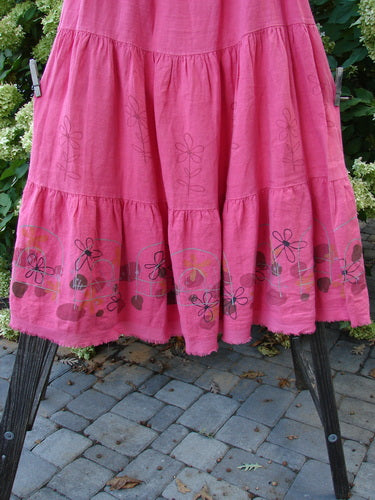 A Barclay Linen Fold Over Three Tier Skirt in Flamingo, featuring a pink skirt with a frill on it. Perfect for a springy look with a sweet frayed lower batiste hem. Size 2.