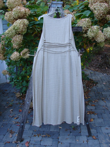 1998 Linen Knit Wrap Dress Unpainted Natural Size 2 displayed on a rustic ladder outdoors, featuring a round neckline, dropped armholes, and waist ties. The dress showcases graceful drape and slender, elegant design.