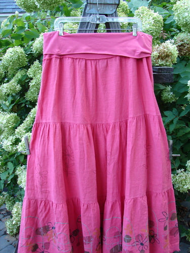 A Barclay Linen Fold Over Three Tier Skirt in Flamingo, featuring a pink skirt on a clothes line. The skirt has a full cotton lycra waistline panel, triple horizontal tiers, and a sweet frayed lower batiste hem. Perfect for a springy look.