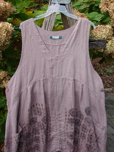 Barclay Linen Pleated Pocket Pinafore Mandala Soft Mauve Size 2: Loose-fitting, sleeveless dress with scoop neckline, side pockets, and mandala print on lower half, hung outdoors on a hanger.