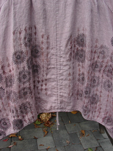 Barclay Linen Pleated Pocket Pinafore Mandala Soft Mauve Size 2 draped on a bench, featuring circular mandala designs, vertical seam, and a drawstring at the hem, reflecting artistic elegance.