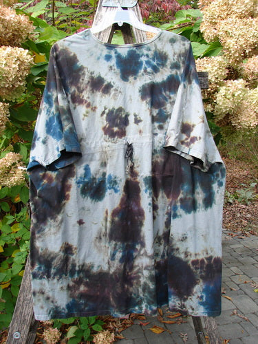 Barclay Drawcord Art Top Mottled Night Storm OSFA displayed on a garden ladder, showcasing its loose fit, tie-dye pattern, drawstring waist, and wide sleeves against a hydrangea backdrop.
