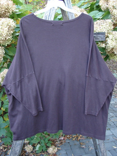 Barclay NWT Modern Square Top Metallic Village Loam Ogo OSFA hangs on a weathered wooden ladder, showcasing its loose fit, dolman shoulders, rounded neckline, and intricate village-themed design in an outdoor garden setting.