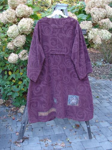 2000 Patched Upholstery Diwmach Coat Celtic Time Aubergine Size 2, displayed on a stand, showcasing its deep purple hue, subtle swirl pattern, colorful Celtic-themed patches, and detailed back pleats.