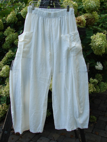 A white linen pants with side pockets on a clothes rack.