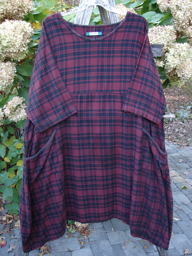 Barclay Flannel Bottom Bell Pocket Dress Merlo Plaid Size 2 features a knee-length, loose fit with a round neckline, wide three-quarter sleeves, and side pockets, displayed outdoors on a wooden hanger.