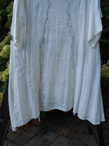 Barclay Linen Venetian Vented Tunic Dress String of Light White Size 1 hanging against a stone backdrop, showcasing its V neckline, A-line shape, and double front drawcords.