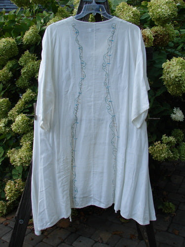 Barclay Linen Venetian Vented Tunic Dress String of Light White Size 1 displayed on an outdoor swing, showcasing its curved seams, softly dipped V neckline, A-line shape, and double front draw cords.