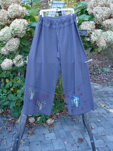 Barclay Wide Leg Bottom Panel Pant Treehouse Brum Size 2, featuring a slate-gray loose fit with unique hand-painted motifs and elastic waistband, displayed on a wooden ladder, embodying Bluefishfinder.com's artistic vintage style.