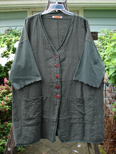 Barclay Cotton Sleeve Pocket Cardigan Unpainted Black Forest Size 1: Long grey shirt with red buttons, wooden buttons, upward curved hemline, deeper V neckline, drop shoulders, curly sleeves, and front pockets.