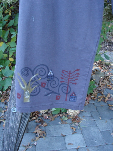Barclay Wide Leg Bottom Panel Pant Treehouse Brum Size 2, featuring whimsical house and nature motifs along the hem, draped over a wooden post, showcasing unique seams and elastic waist with drawstring.