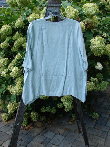 Image alt text: Barclay Linen Cross Dye T Top Unpainted Sage Size 1 - A shirt on a rack, featuring a swinging A-line shape, varying hemline, and side vents. Made from medium weight cross dye linen. Perfect condition from the Spring Collection of 2000.