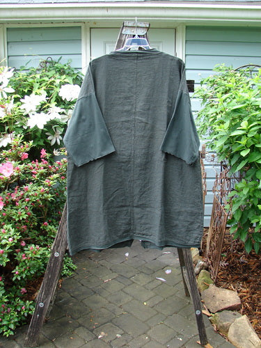 Barclay Cotton Sleeve Pocket Cardigan Unpainted Black Forest Size 1 displayed on a clothes rack, featuring wooden buttons, drop shoulders, and squared-off pockets with a curved hemline.